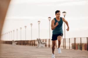 Athletic man sprinting on boardwalk outside
